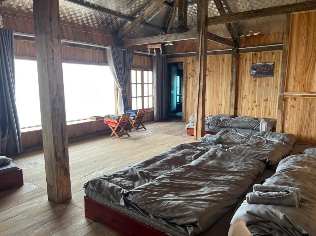 1 dormitorio con 2 camas en una habitación con paredes de madera en MOONG Homestay & Coffee Tà Xùa en Bắc Yên