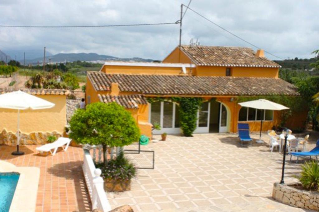 テウラーダにあるFinca Vicente - charming, Finca style holiday villa in Teuladaのスイミングプールとパティオ付きのオレンジハウスです。