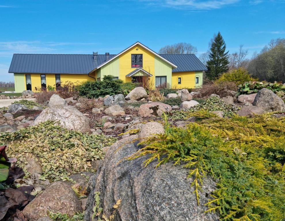 een geel huis met rotsen ervoor bij Auksi motell in Auksi