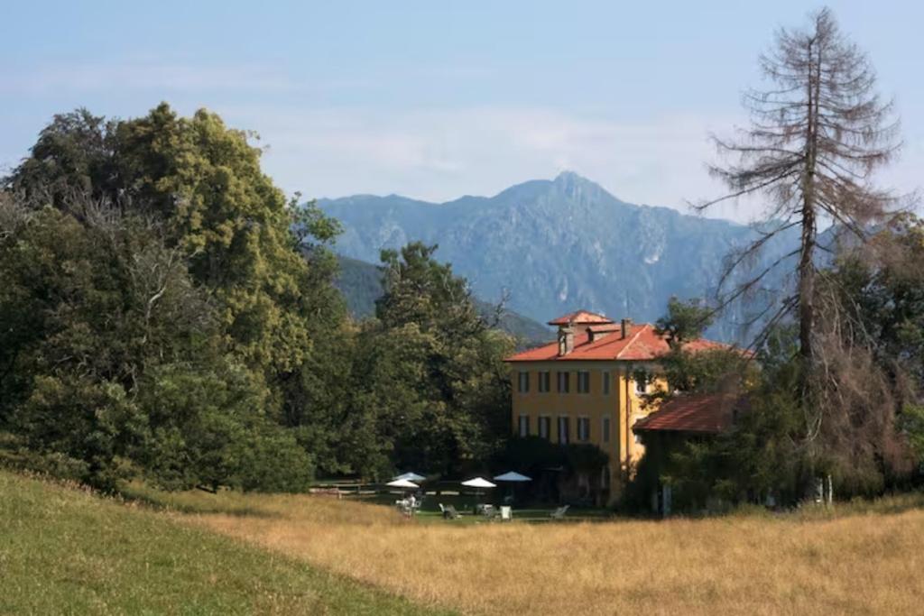 un grand bâtiment jaune au milieu d'un champ dans l'établissement Hotel Villa Simplicitas, à San Fedele Intelvi