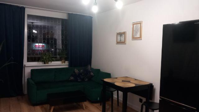 a living room with a green couch and a table at Apartament Portowa OSTOJA in Gdańsk