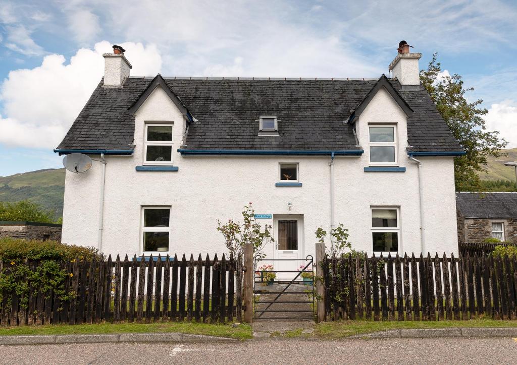 a white house with a fence in front of it at Duart Cottage in Glencoe