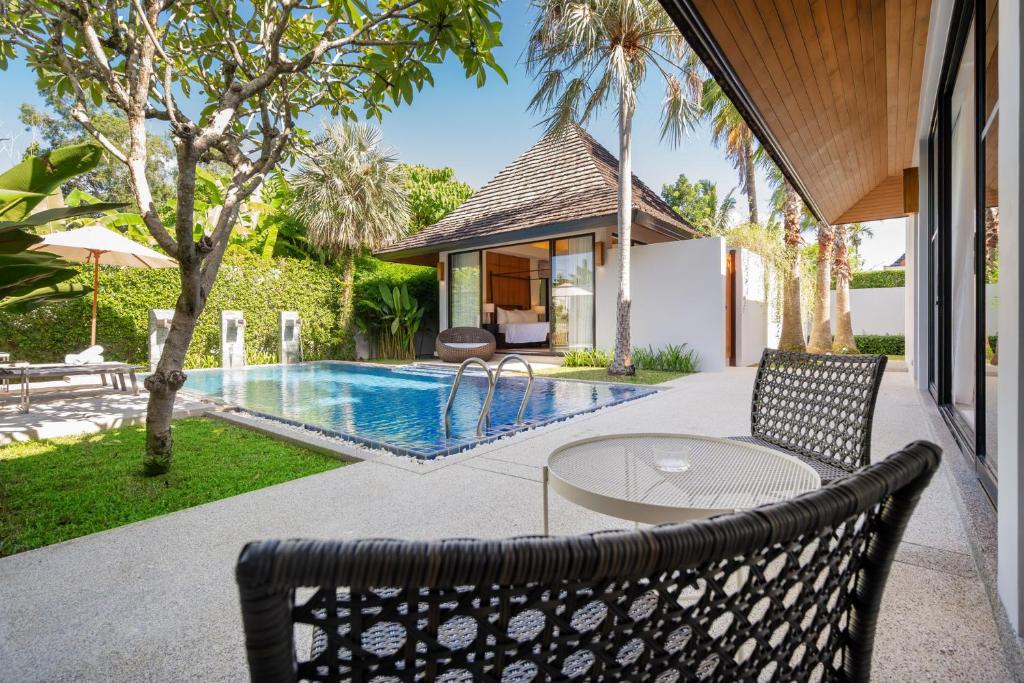 un patio con mesa y sillas junto a una piscina en Escape Villas - Luxury Pool Villa at Anchan Villas en Ban Phru Champa