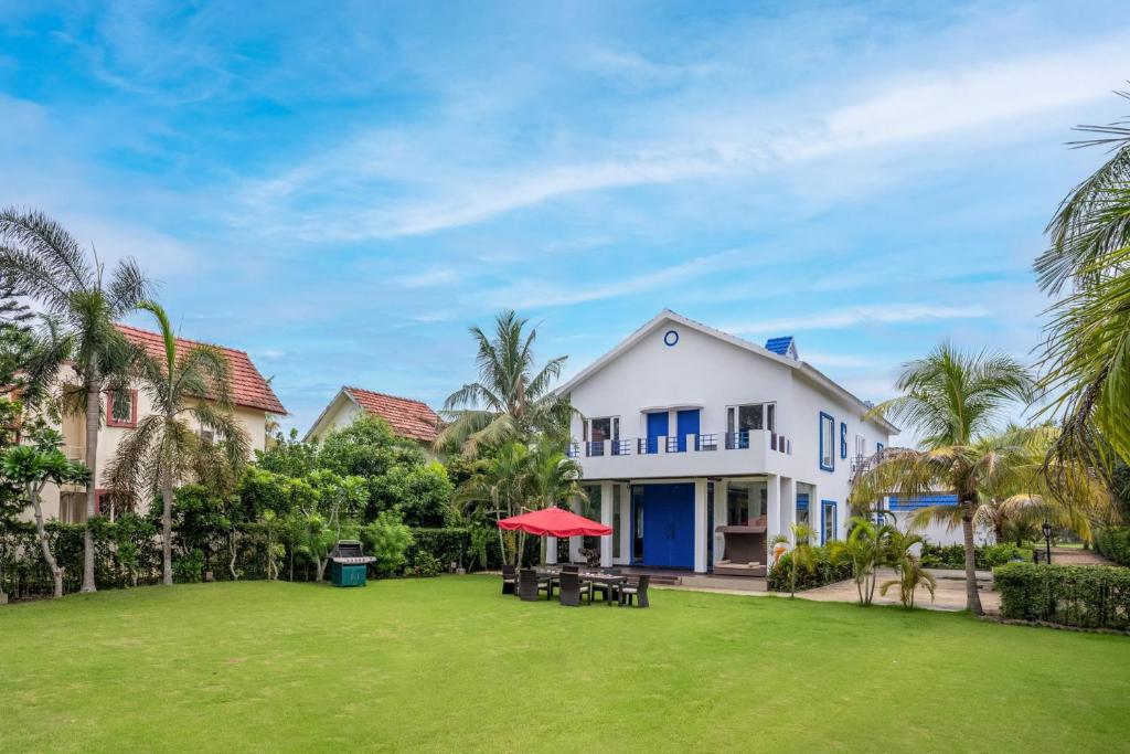 une maison avec une pelouse devant elle dans l'établissement Timeless Elegance by StayVista - Poolside Villa with Lawn & Terrace, à Kolkata