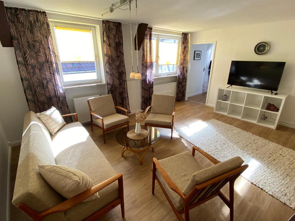 uma sala de estar com um sofá e cadeiras e uma televisão em Ferienwohnung am Schmetterlingssteig em Trendelburg