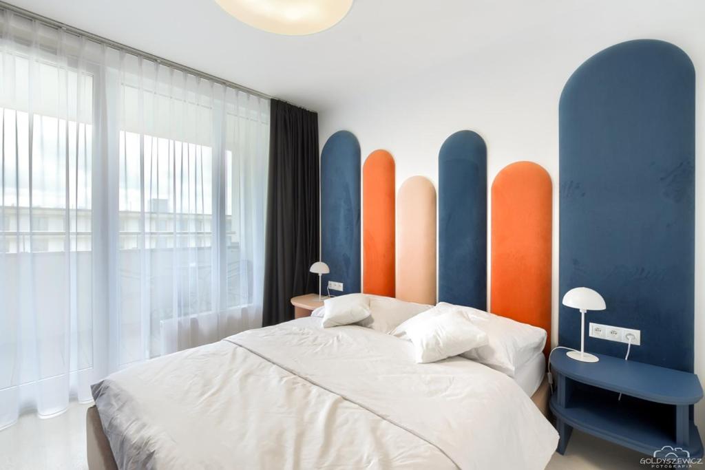 a bedroom with a bed and a blue and orange wall at Apartament SPA z Prywatną Sauną Parową in Kołobrzeg