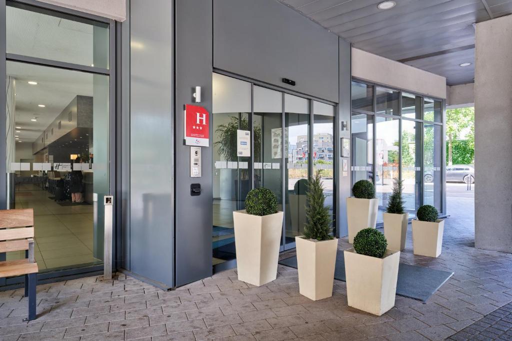 un bâtiment de bureau avec des plantes en pot devant une porte dans l'établissement Holiday Inn Express Strasbourg Centre, an IHG Hotel, à Strasbourg