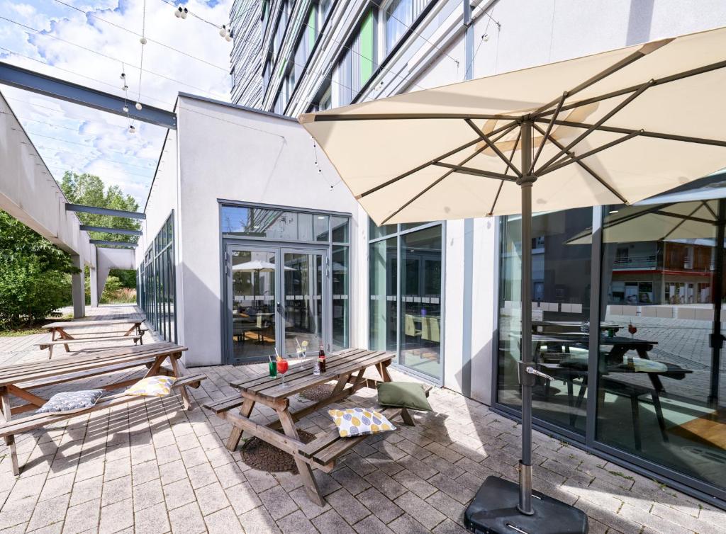 eine Terrasse mit Bänken und einem Sonnenschirm vor einem Gebäude in der Unterkunft Holiday Inn Express Strasbourg Centre, an IHG Hotel in Straßburg