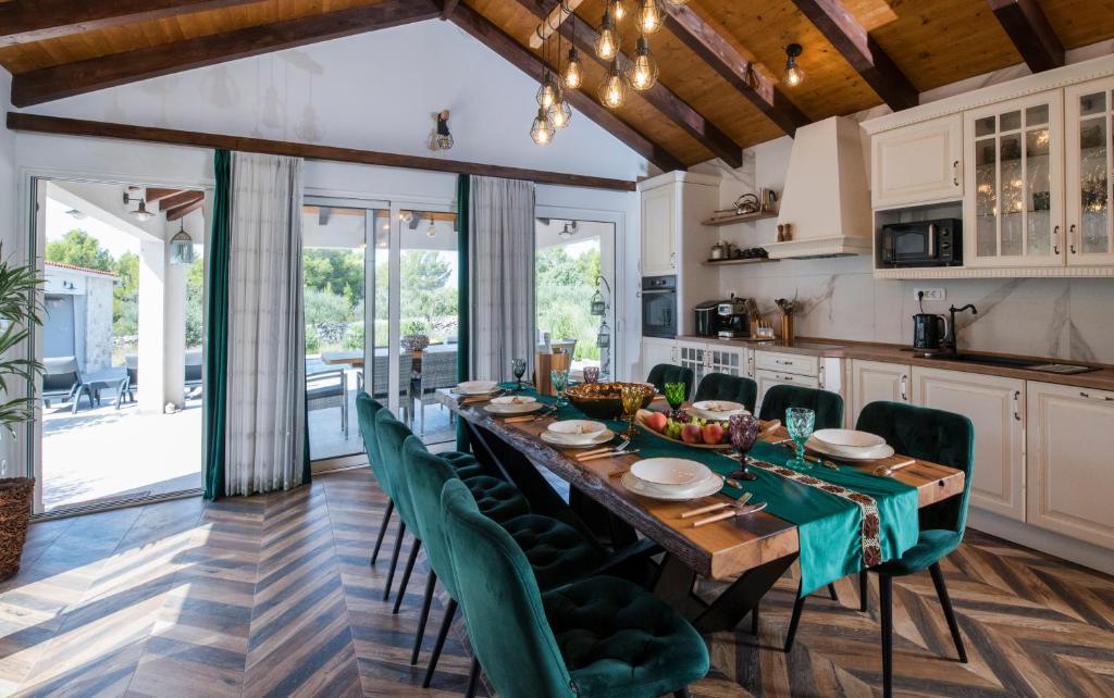 a kitchen and dining room with a long table and green chairs at Luxury Villa Nature with heated private pool, sauna & fire pit, a short walk to the beach in Milna
