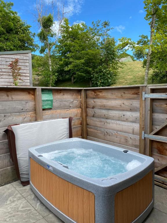 bañera de hidromasaje en un patio con 2 sillas en Badger Lodge with Hot Tub, en Cupar