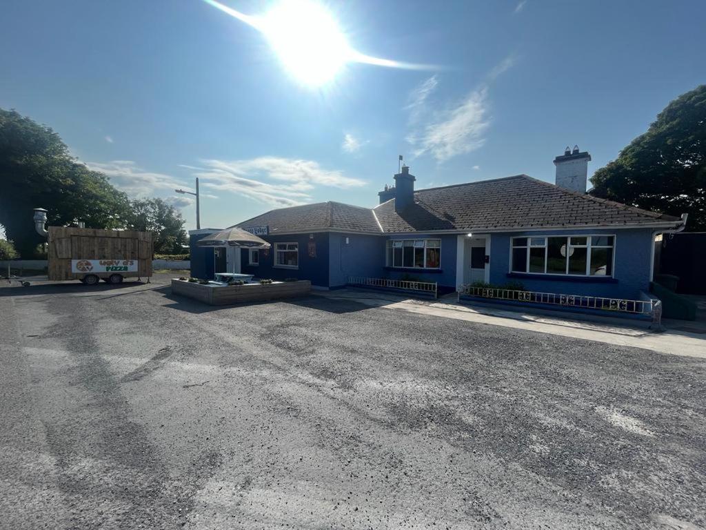 uma casa azul com o sol no céu em Yeats Lodge Self catering Apartment and Bar em Galway
