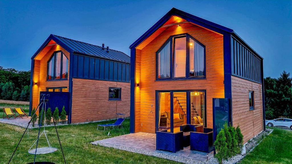 a house with glass doors on a yard at Domki Diabolina - sauna, jacuzzi, klimatyzacja, kominki in Krajno Pierwsze