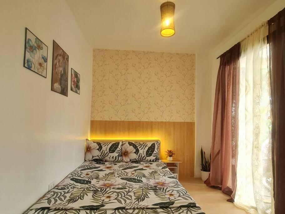 1 dormitorio con 1 cama con colcha de flores en Muji-inspired Home, 2-BR Bungalow Home Trece Martires, en Trece Martires