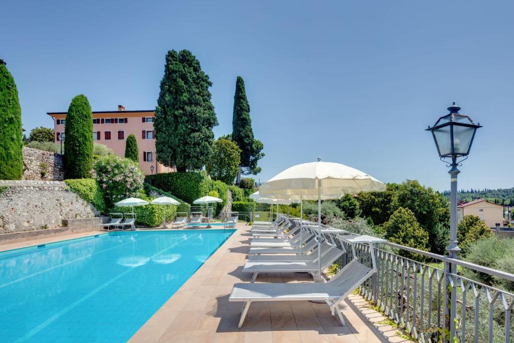 a swimming pool with lounge chairs and an umbrella at Residence La Filanda in Costermano