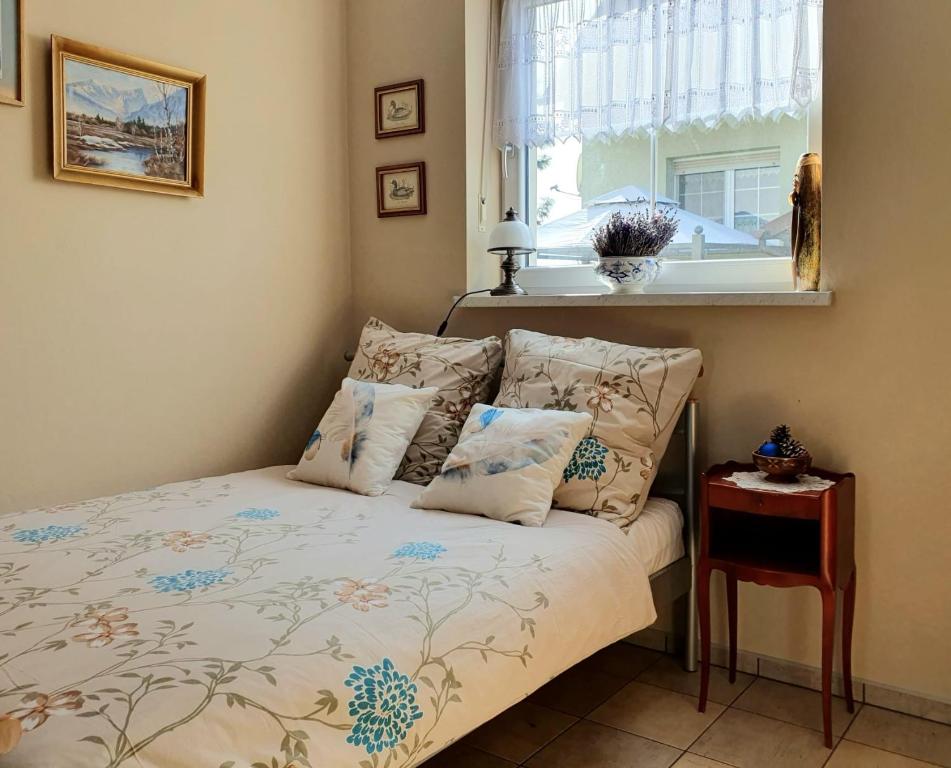 1 dormitorio con cama con almohadas y ventana en Lawendowa Galeria MINI, en Brożec
