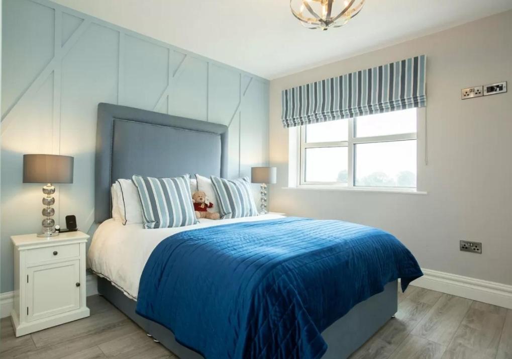 a bedroom with a large bed with a blue blanket at Louth Village Wedding Accommodation with Gym B&B in Lubhaidh