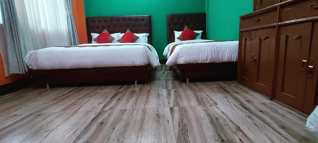 2 camas en un dormitorio con paredes verdes y suelo de madera en Nepalaya Home Hostel, en Katmandú