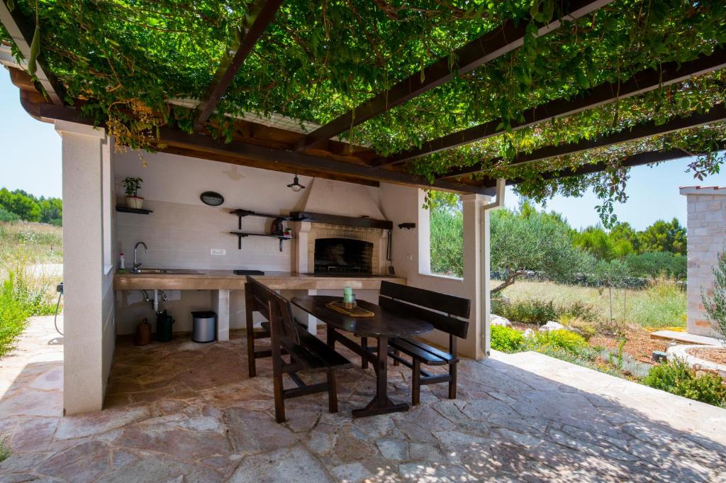 an outdoor kitchen with a table and chairs under a pergola at Luxury Villa Nature with heated private pool, sauna & fire pit, a short walk to the beach in Milna