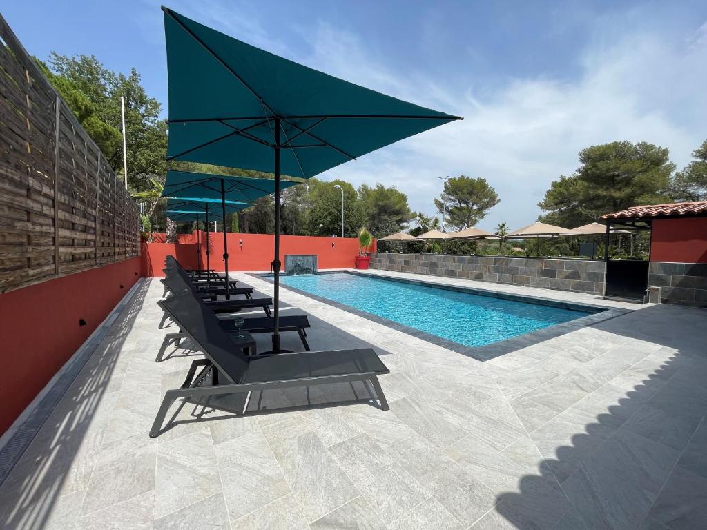 - une piscine avec des chaises longues et un grand parasol dans l'établissement Urban Style Cannes Mouans-Sartoux - Piscine Extérieure - Parking Gratuit, à Mouans-Sartoux