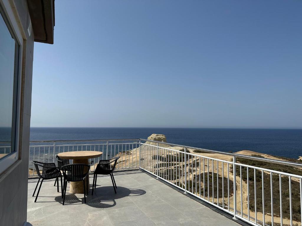 a balcony with a table and chairs and the ocean at Salini Suites in Żebbuġ