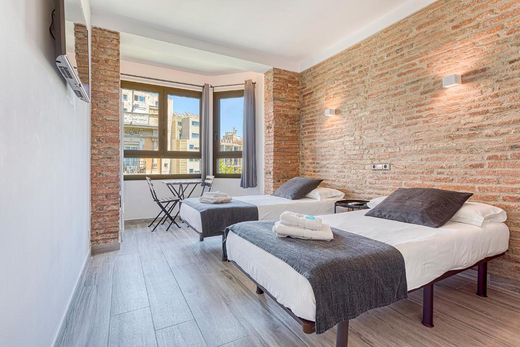 two beds in a room with a brick wall at HOSTAL BEDMATES in Barcelona
