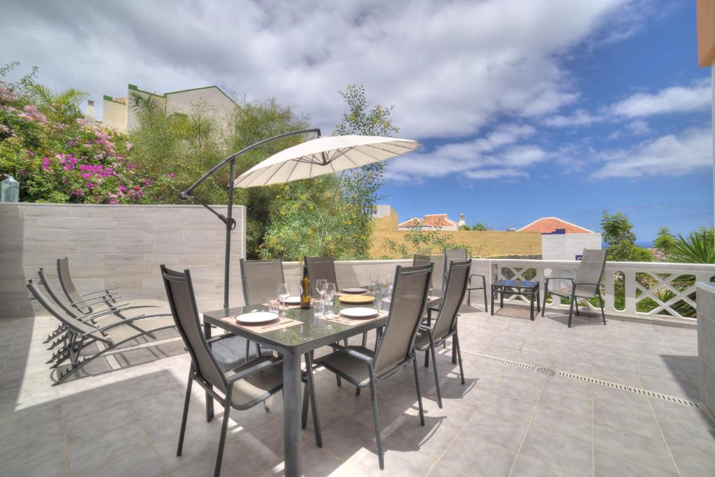 een patio met een tafel en stoelen en een parasol bij Ocean Hill - Ocean View, Terrace, BBQ, WIFI in Adeje