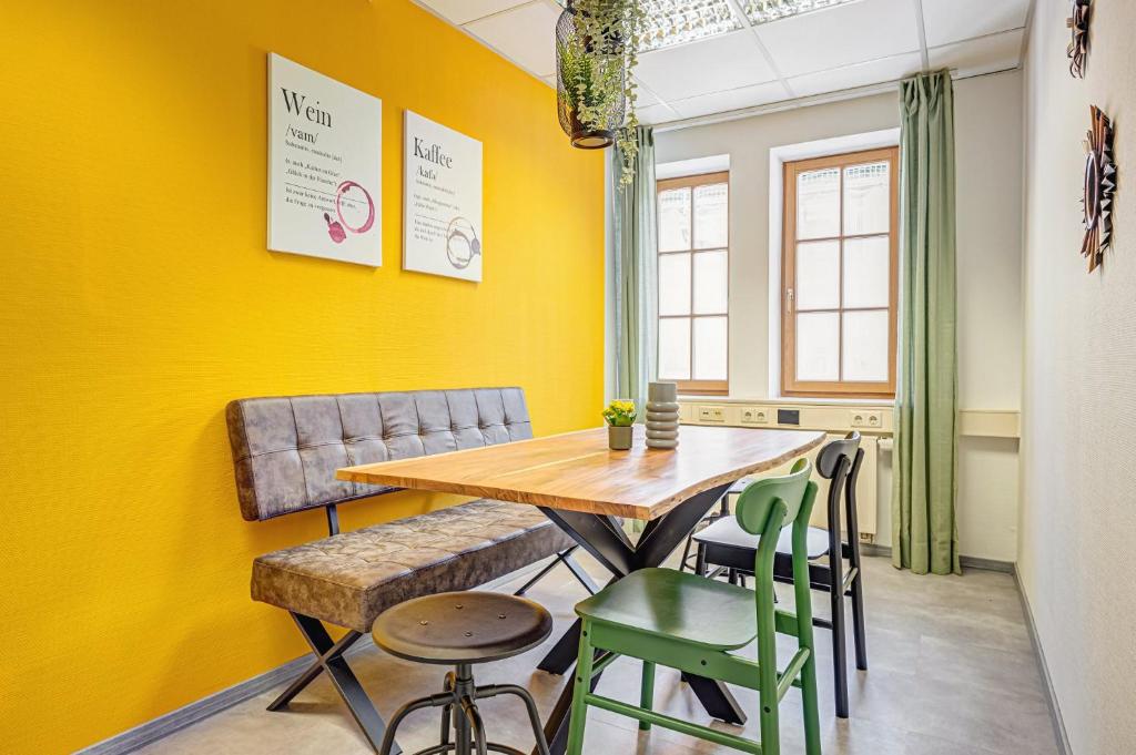 ein Esszimmer mit gelben Wänden, einem Holztisch und Stühlen in der Unterkunft Pressehaus Apartment Obermarkt One in Mühlhausen