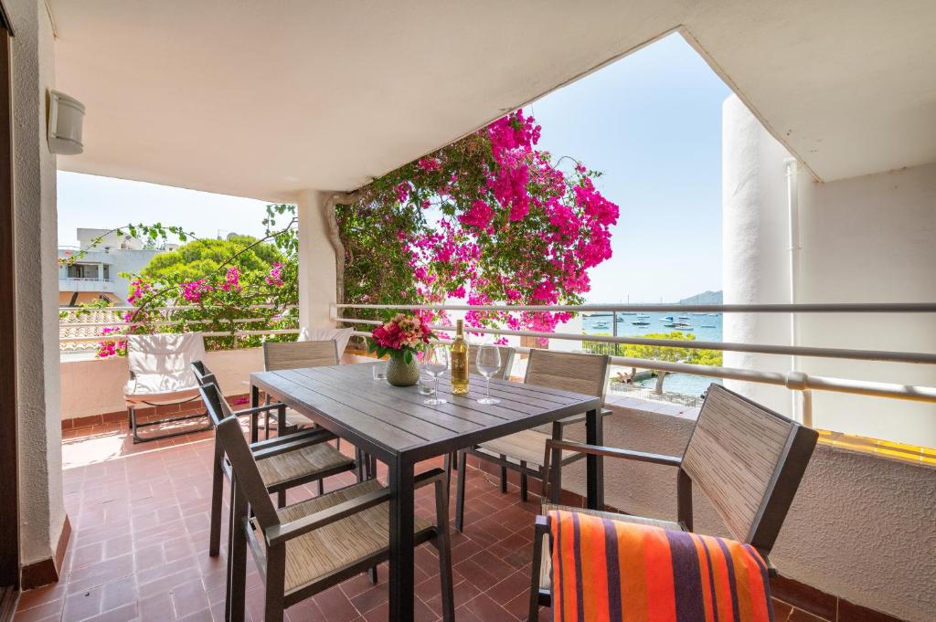 uma mesa e cadeiras numa varanda com flores em El Barco em Port de Pollença