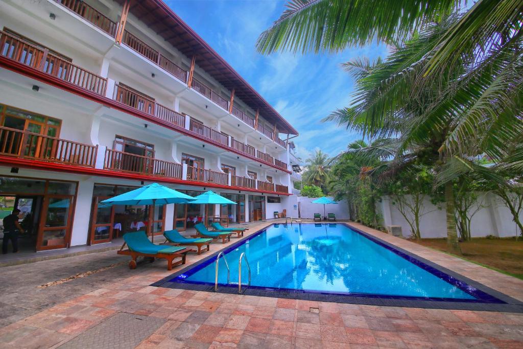 a swimming pool in front of a building at Rockside Beach Resort in Bentota