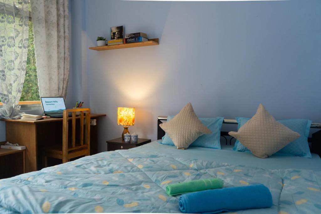 a bedroom with a blue bed with pillows and a desk at Basant Hritu Homestay in Kalimpong