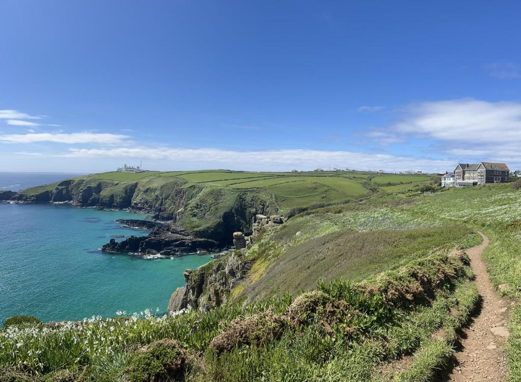 a house on a cliff next to the ocean at Housel Bay Hotel in Lizard