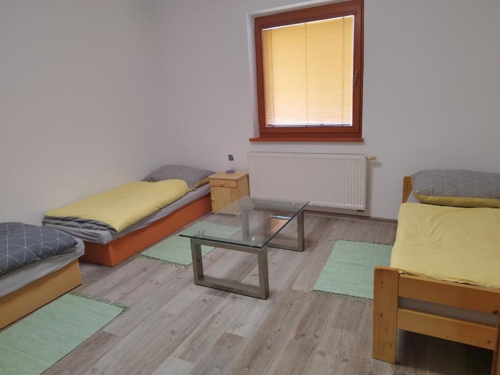 Habitación con 2 camas, mesa y ventana en Ubytovanie Vo dvore en Badín