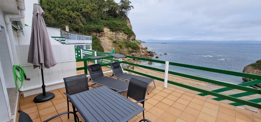 Un balcón con sillas, una sombrilla y el océano. en Rincón de Mar - En Playa Estaño, en Gijón
