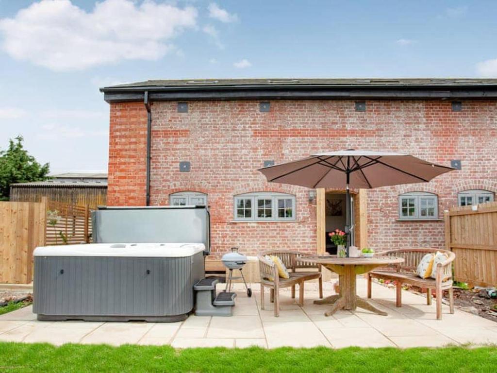 a hot tub and a table with an umbrella at Cosy cottage in the Blackdown hills Devon in Honiton