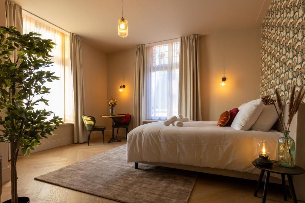 a bedroom with a large white bed and a table at Boetiek hotel bij Jacob in Enschede