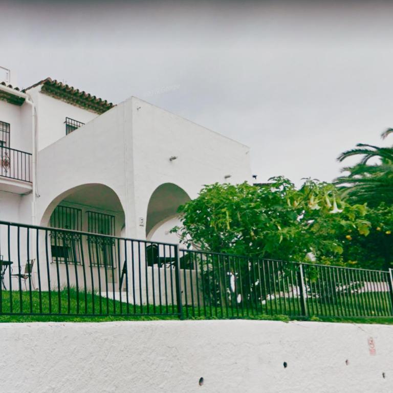 um edifício branco com uma cerca preta em frente em Luminosa casa en Nerja em Nerja