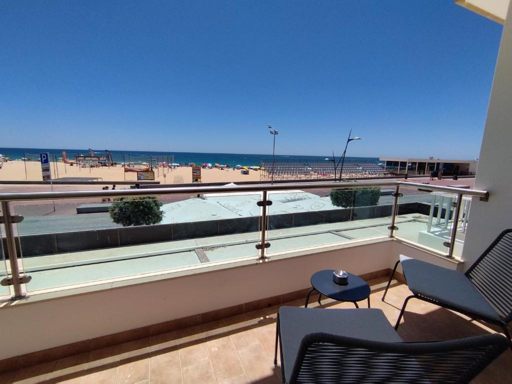d'un balcon avec des chaises et une vue sur la plage. dans l'établissement T2 - Praia Pescadores Frente Mar - Casas & Papéis, à Armação de Pêra