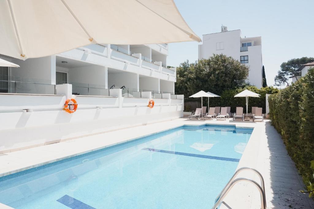 una piscina en un hotel con sillas y sombrillas en Hoposa Pollensamar Apartamentos, en Puerto Pollensa