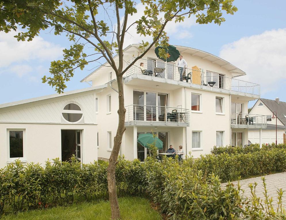 une maison blanche avec des personnes sur le balcon dans l'établissement Villa Sonnenstrand II, à Bansin