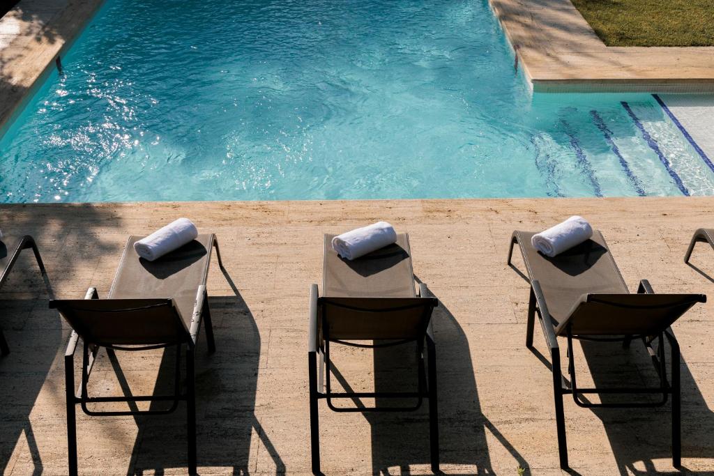 a group of chairs sitting next to a swimming pool at Hotel PAX Torrelodones in Torrelodones