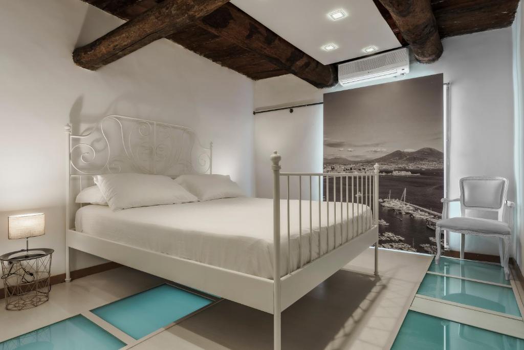 a white bedroom with a bed and a chair at La bella vita luxury apartament and travel solution in Naples