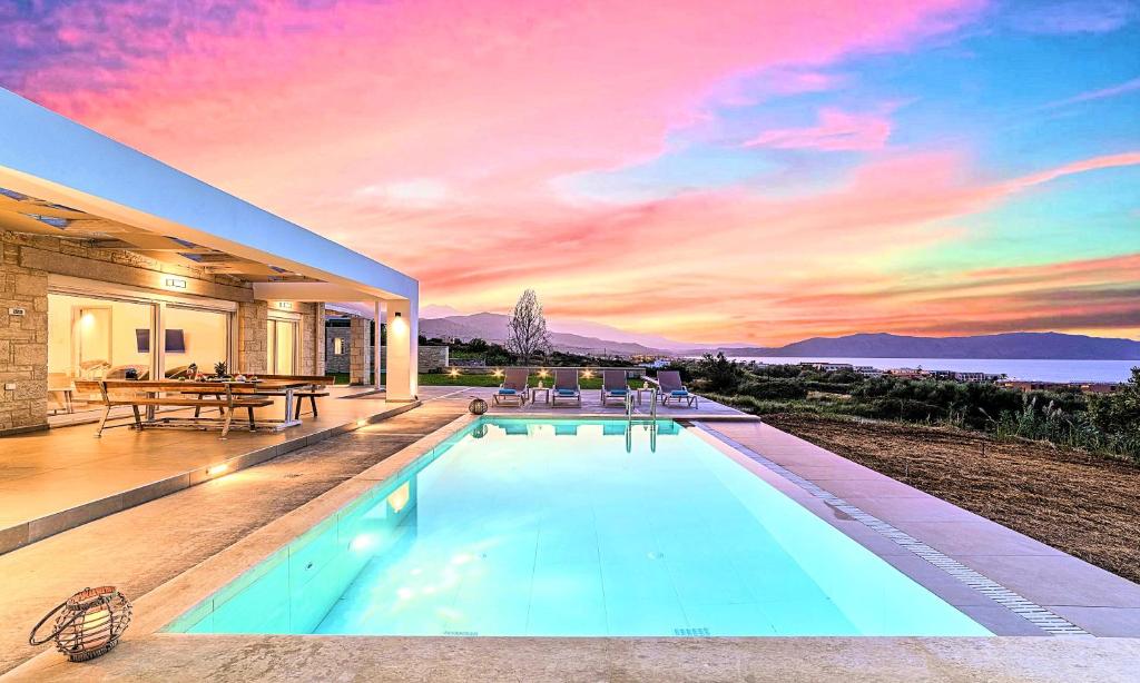 a swimming pool in a house with a sunset at Vista Mare Villas Heated Pool in Georgioupoli