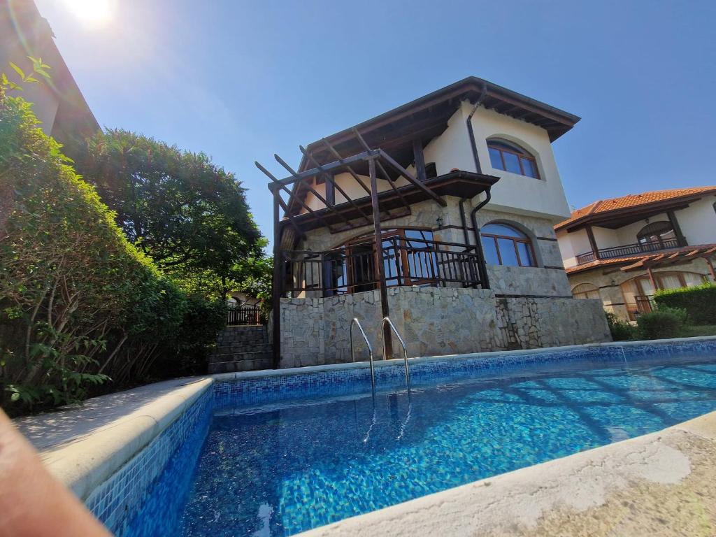 a house with a swimming pool in front of a house at Victoria Villa, 13 Merlot street, The Vineyards resort, Aheloy, Pomorie. in Burgas