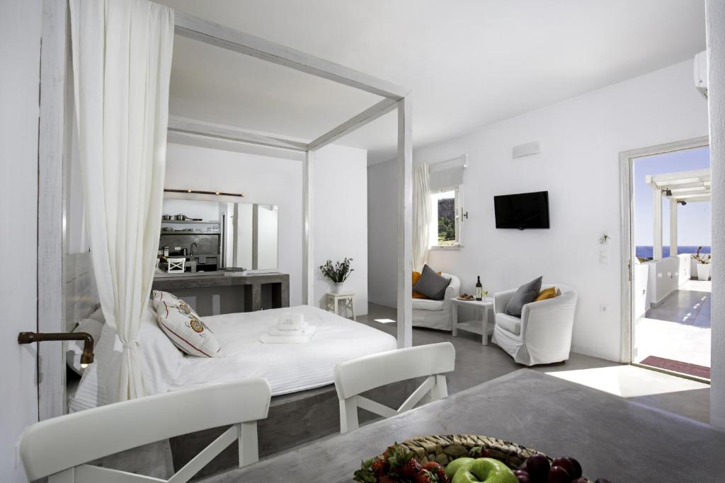 a white bedroom with a bed and a living room at Lindian Pearl in Líndos