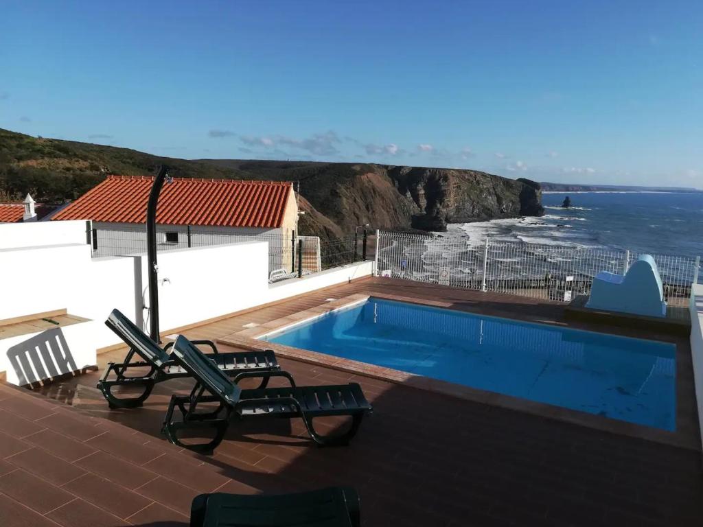 a swimming pool with chairs and a view of the ocean at Pôr do Sol in Aljezur