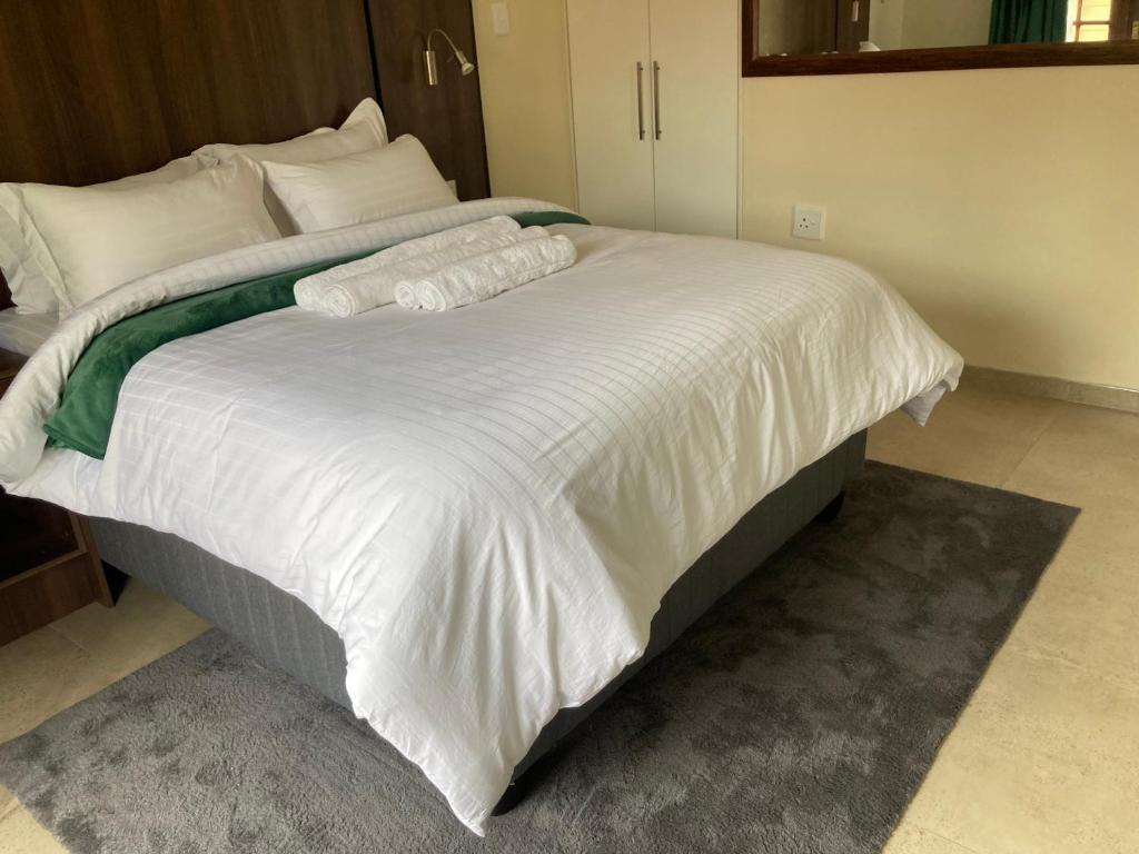 a large white bed with white sheets and pillows at Edenvale corner in Edenvale