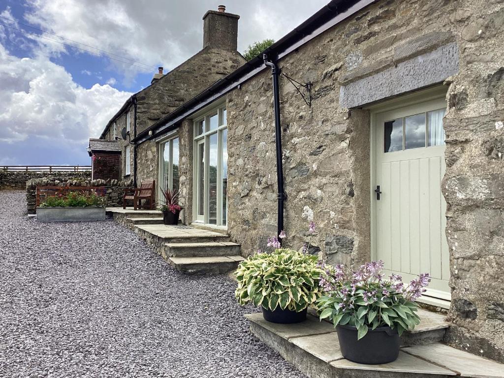 a stone house with a white door and some plants at Y Bwthyn in Betws-y-coed