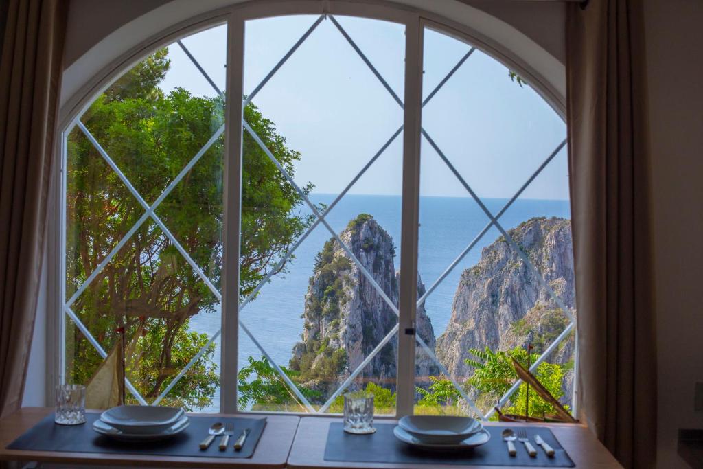 Blick auf das Meer von einem Fenster im Esszimmer in der Unterkunft Faraglionensis MonaconeHouse Apartment in Capri