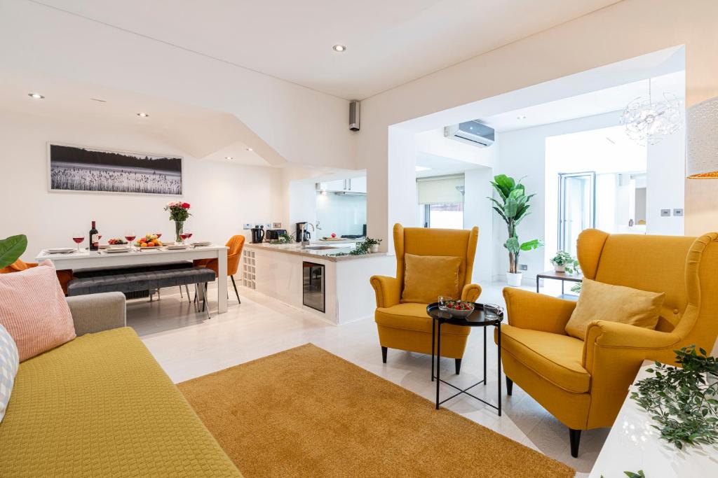 a living room with yellow chairs and a kitchen at Stay at Kensington and Knightsbridge in London