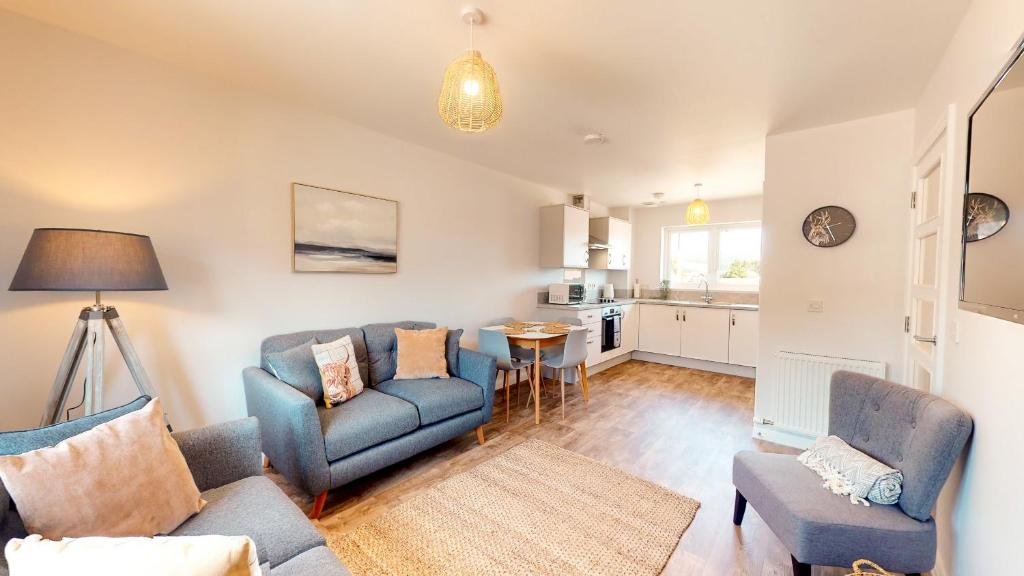 a living room with a couch and chairs and a kitchen at 4 Ben Avon in Aviemore